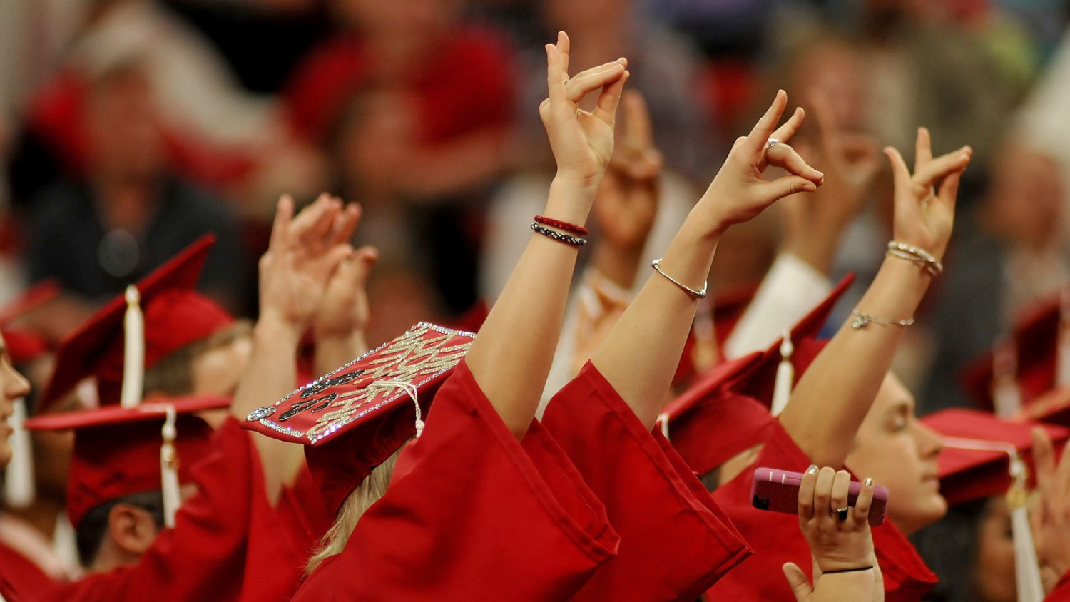 hands of students in graduation robes doing the wolfie