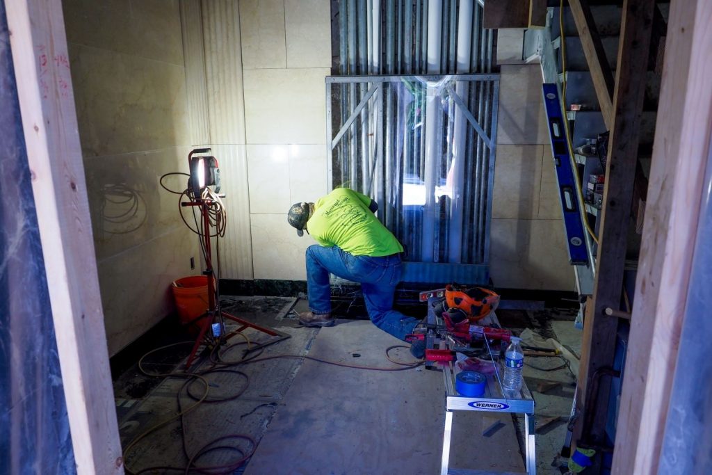 a worker works on the marble walls of the shrine room
