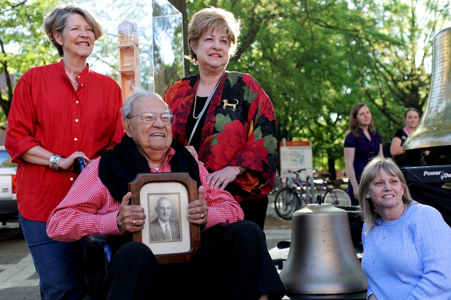 William Morris Jr with family holding a picture of William Morris Sr in front of their bell in 2012
