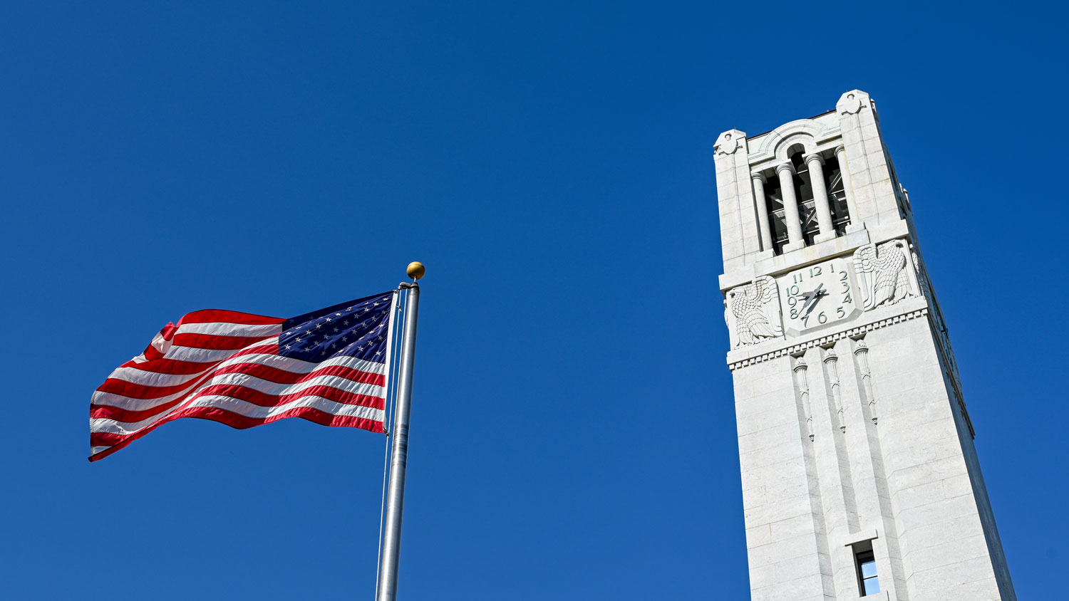 The American flag flies next to the Memorial Belltower